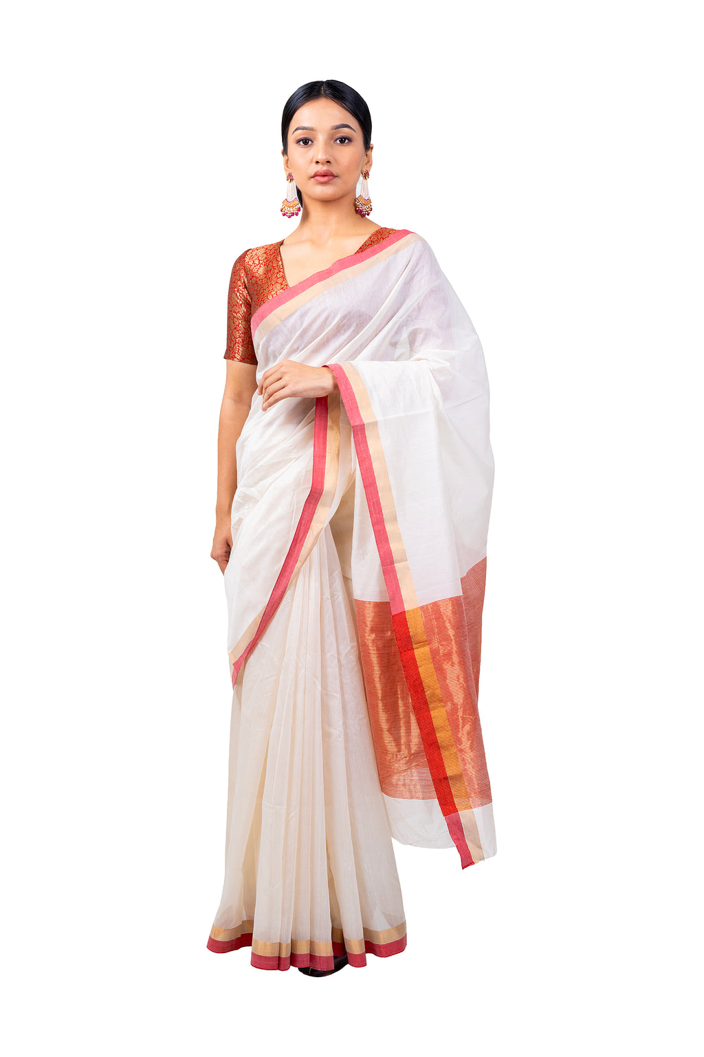 Woman wearing a white saree with red and gold border on a white background