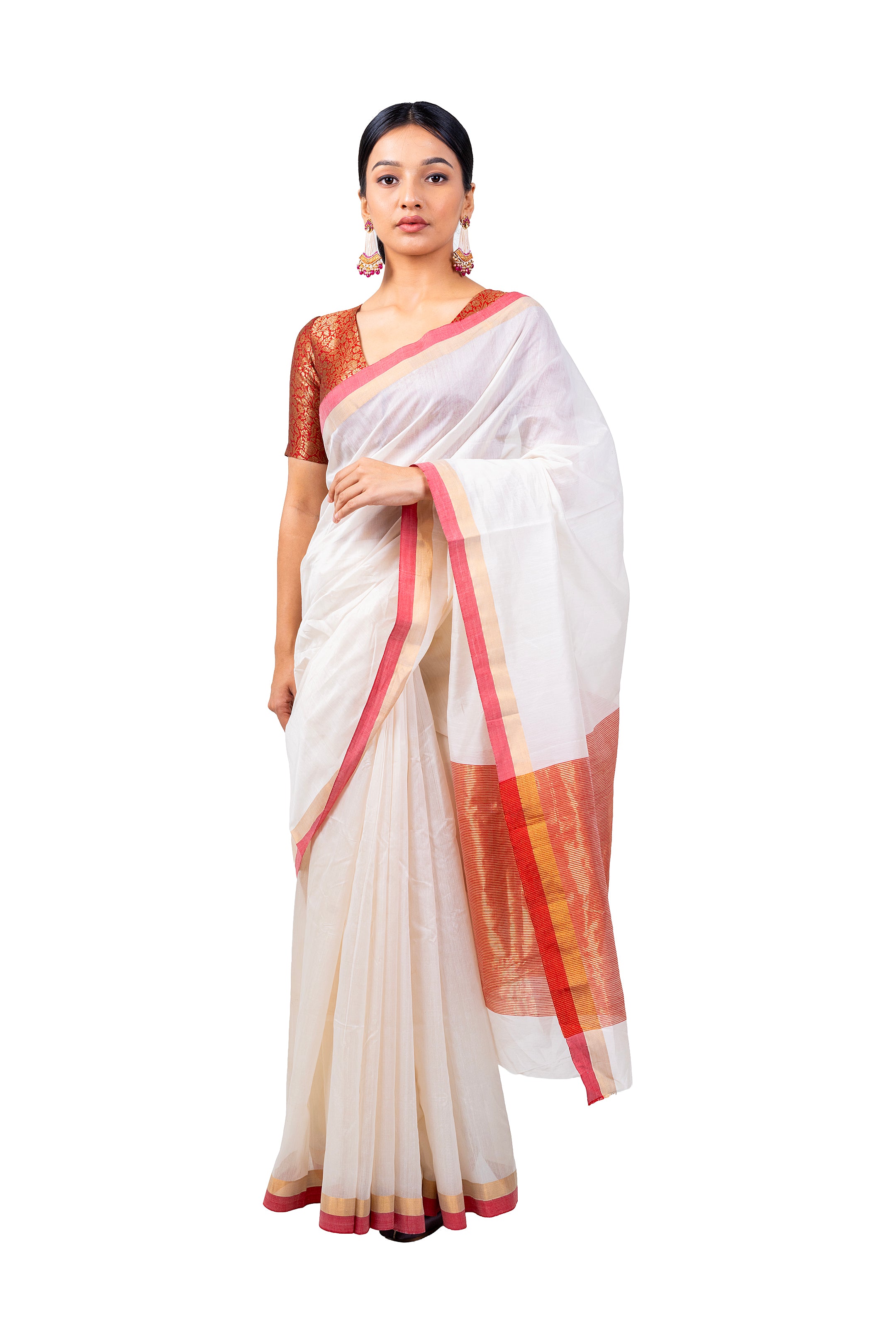 Woman wearing a white saree with red and gold border on a white background
