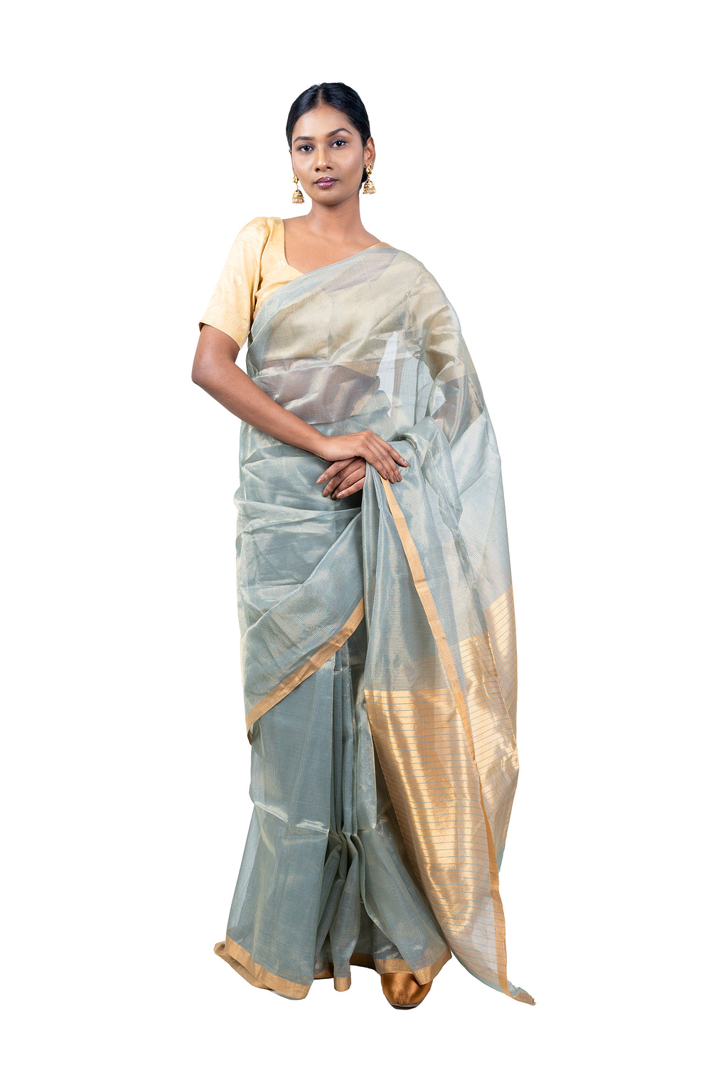 Woman wearing a light gray saree with gold border on a white background