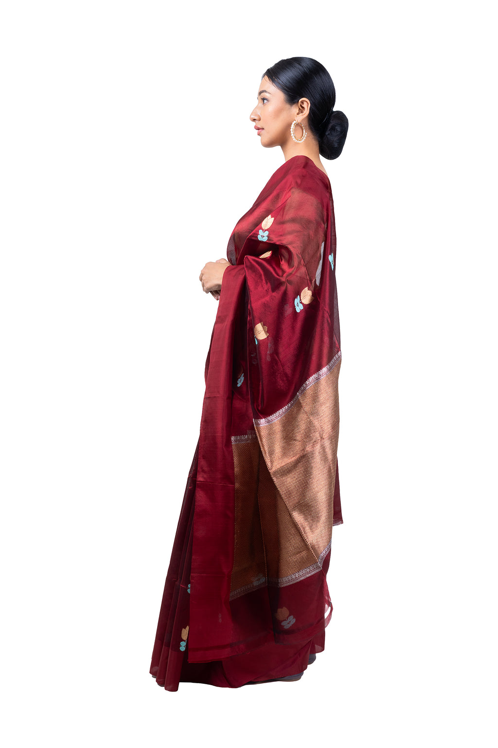 Woman wearing a maroon saree with a gold border on a white background