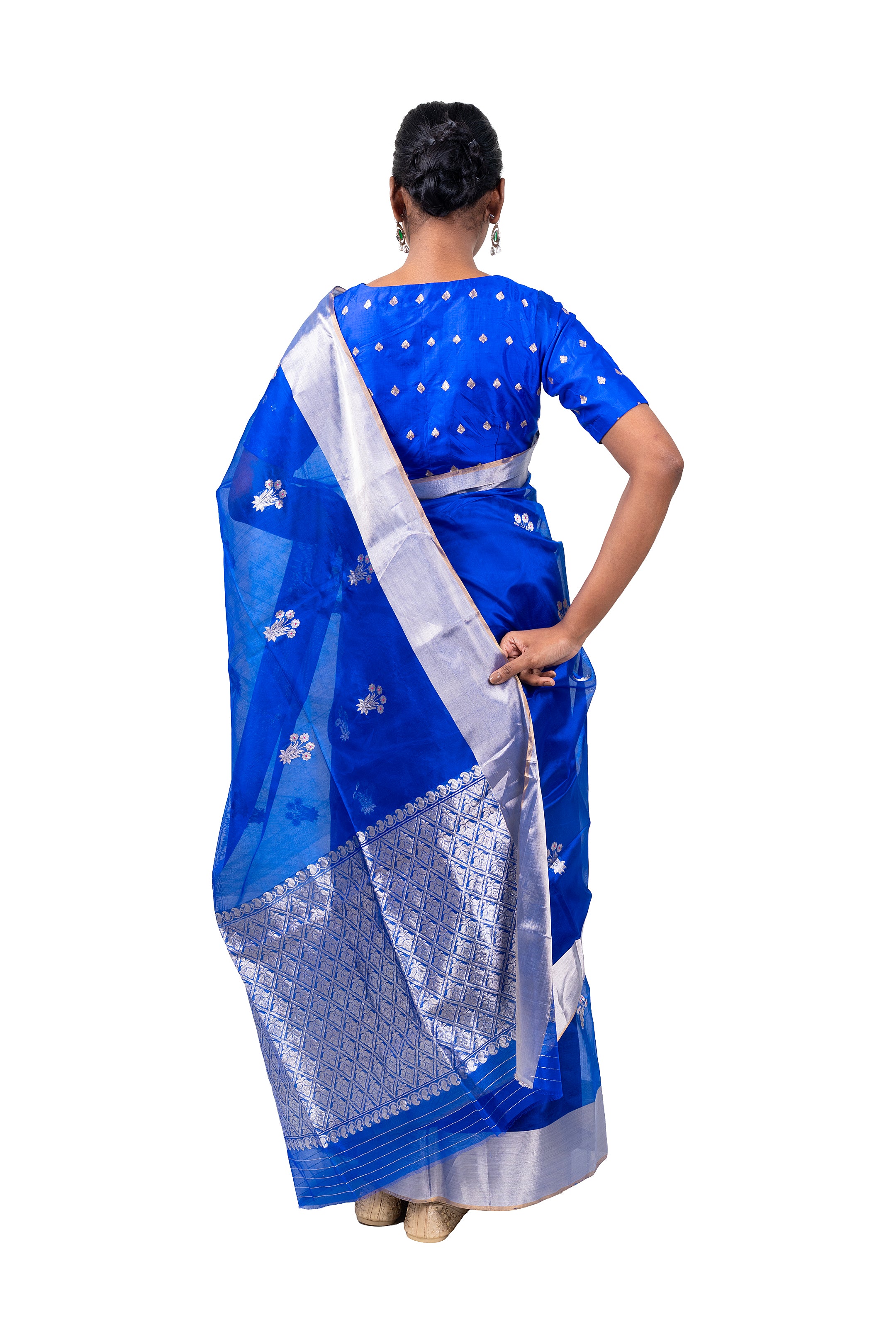 Woman wearing a blue saree with white patterns on a white background