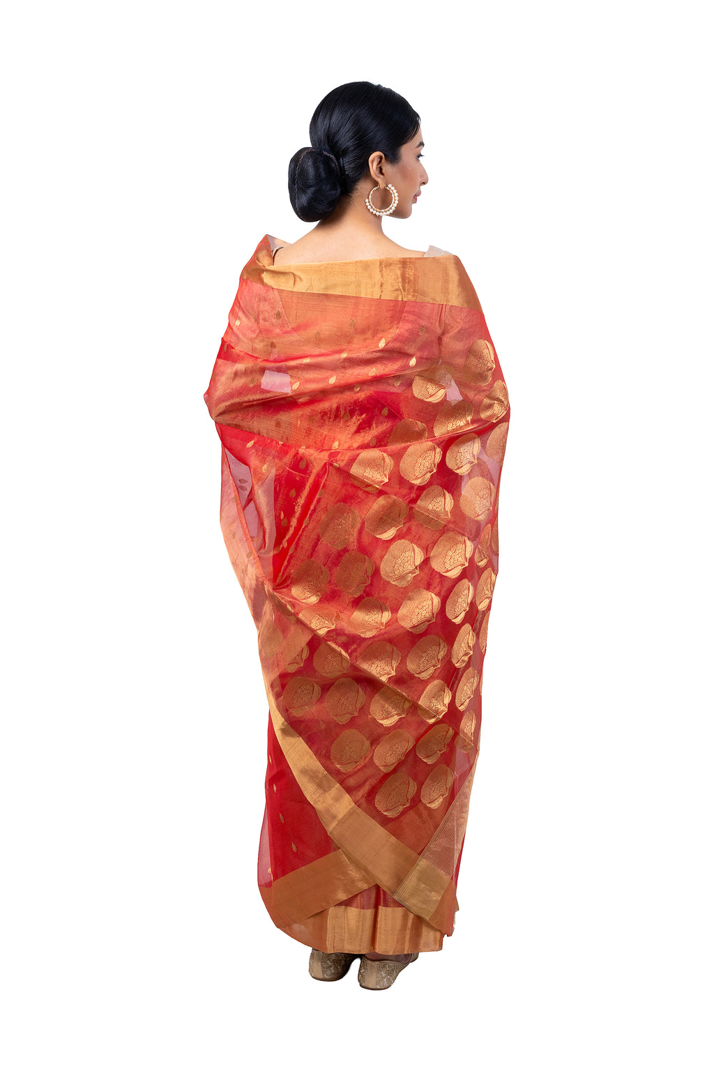 Woman wearing a red saree with gold patterns on a white background