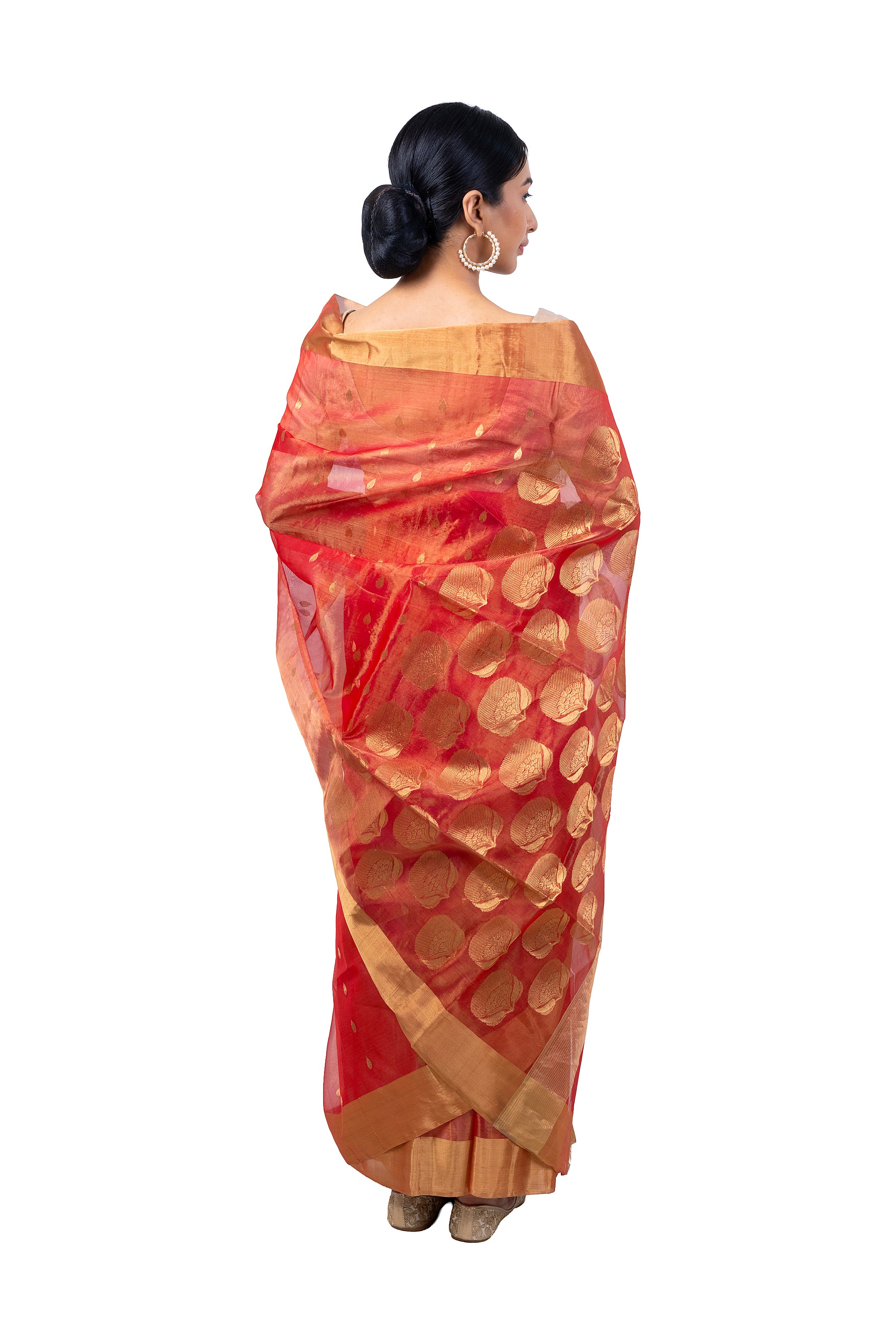 Woman wearing a red saree with gold patterns on a white background