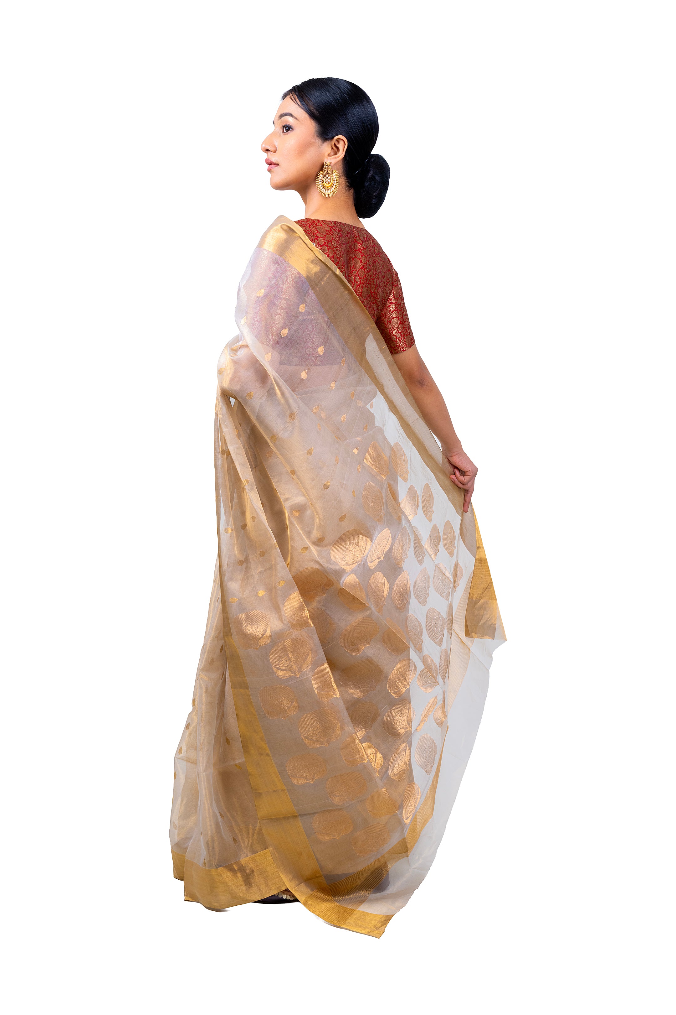 Woman wearing a beige and gold saree with a white background
