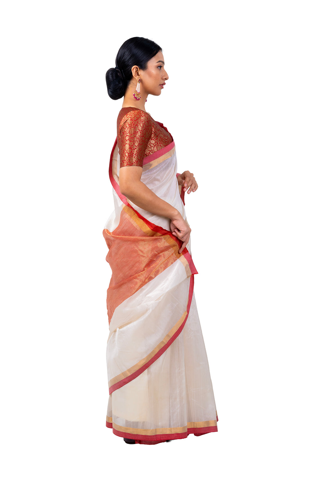 Woman wearing a white saree with red and gold border on a white background