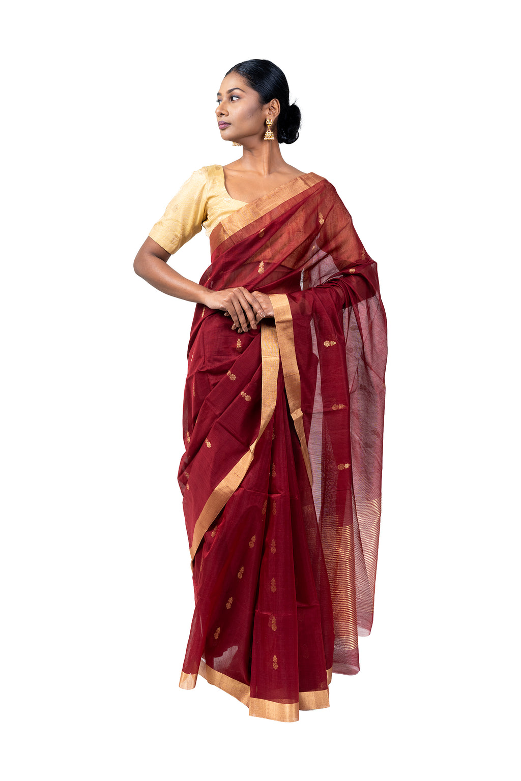 Woman wearing a maroon saree with gold border on a white background