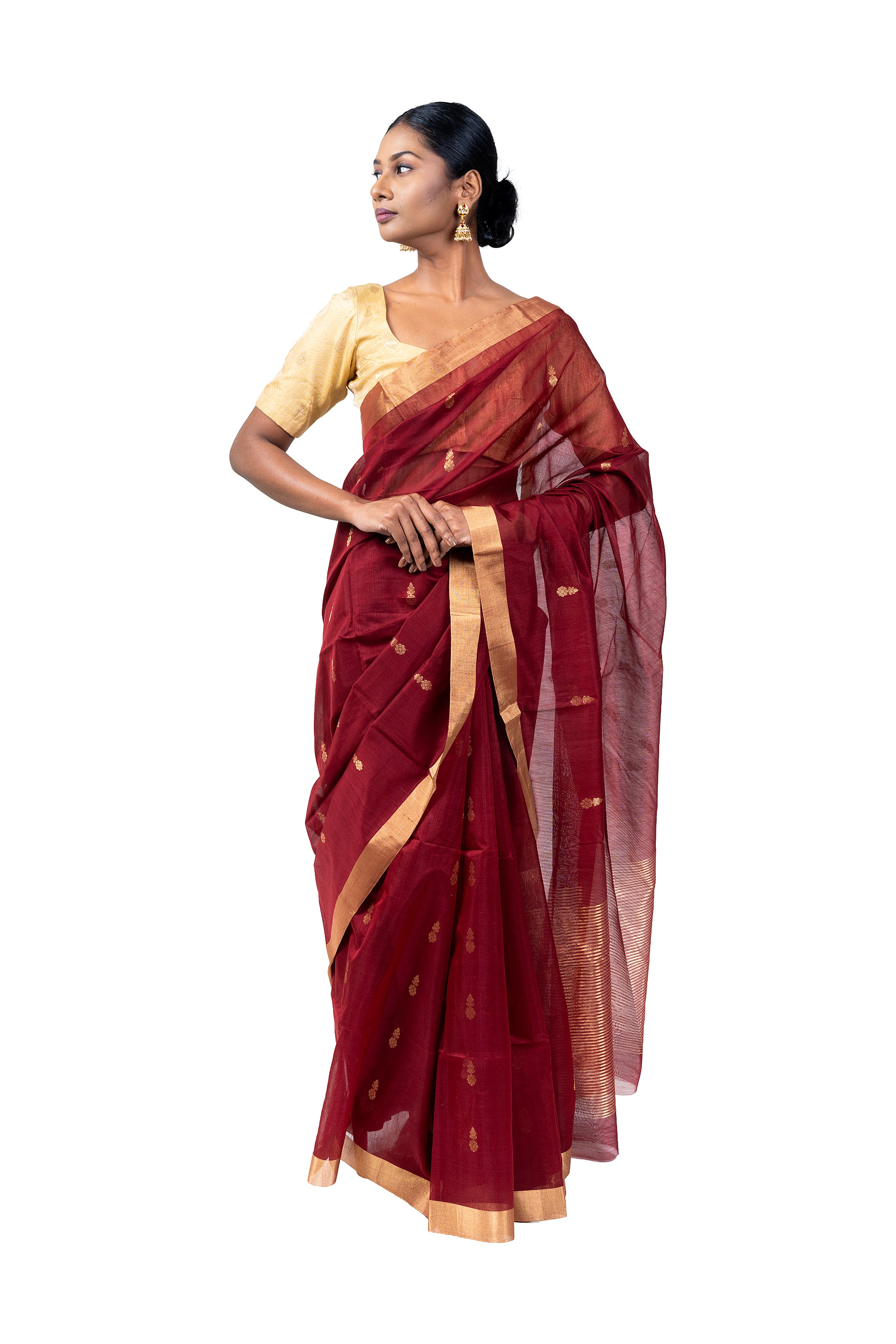 Woman wearing a maroon saree with gold border on a white background