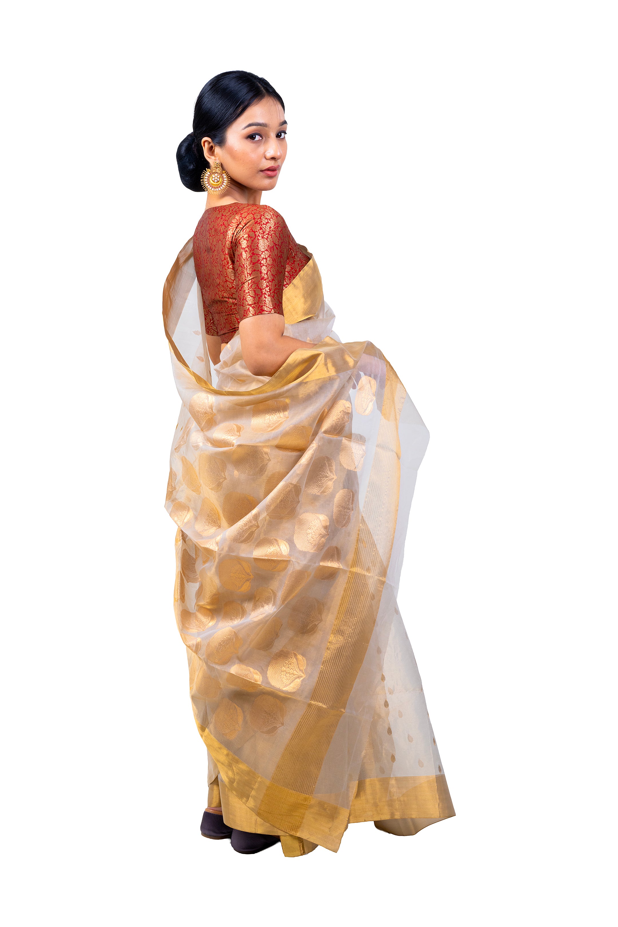Woman wearing a traditional saree with gold and white patterns on a white background