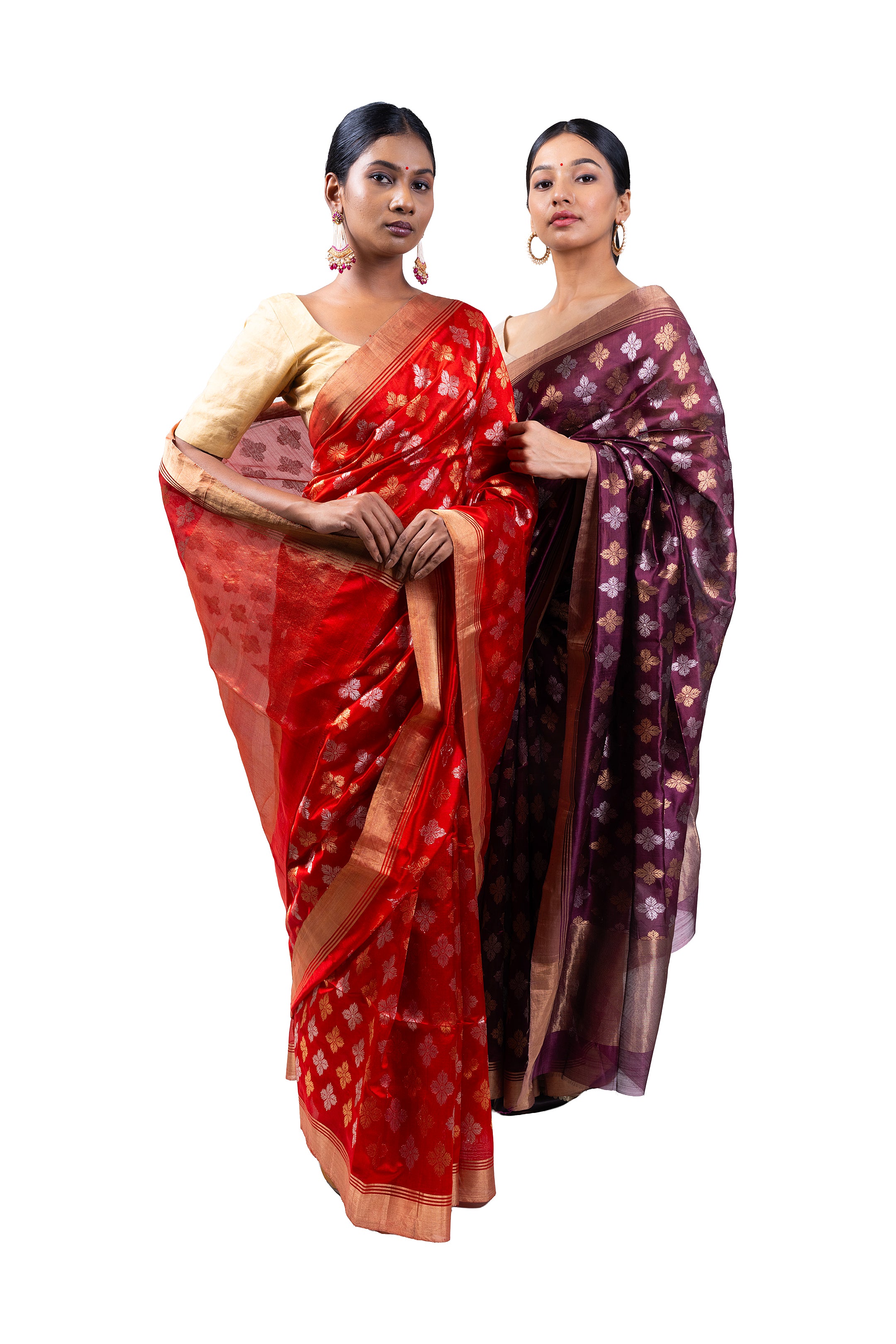 Two women wearing red and purple sarees on a white background