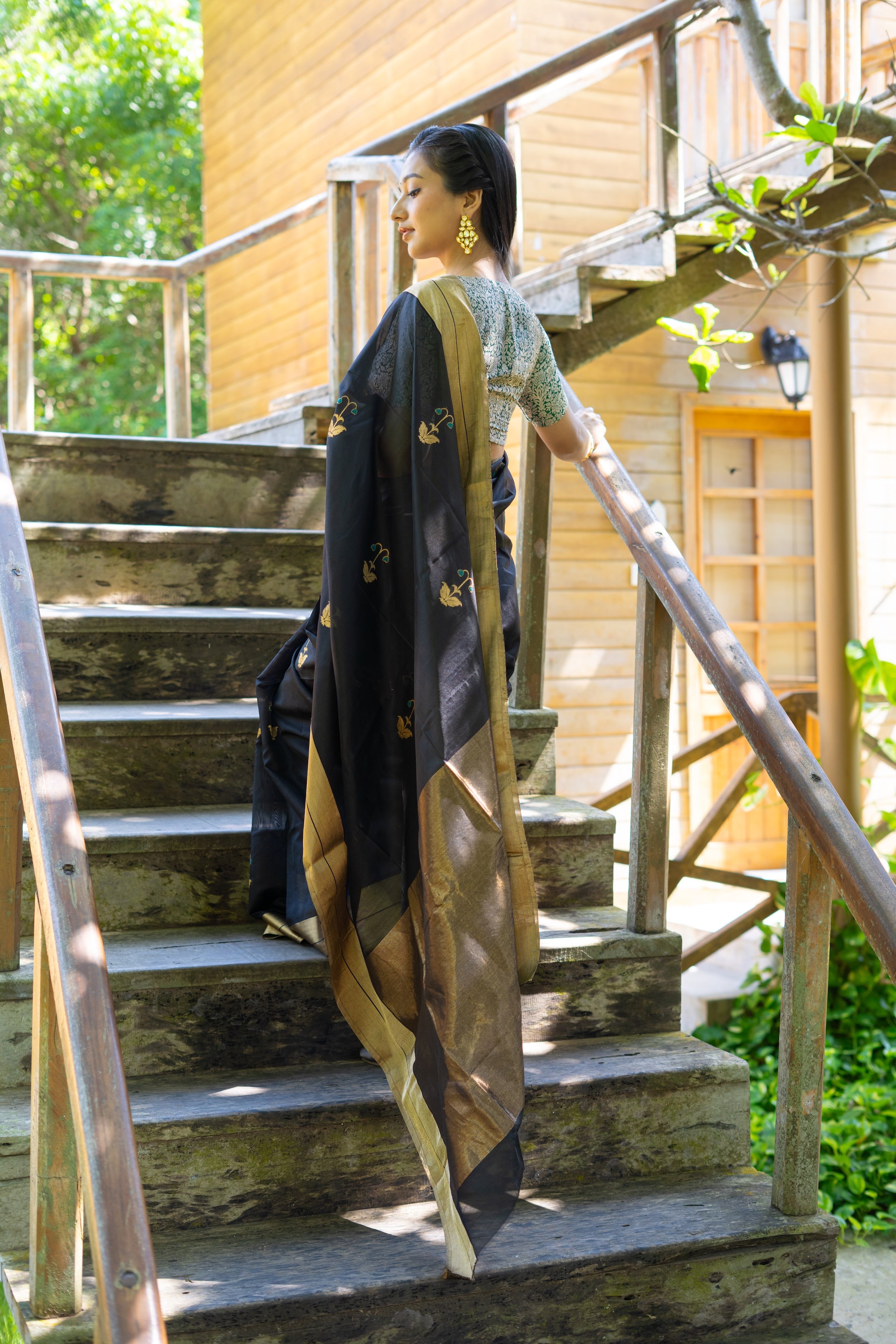 Woman descending wooden stairs wearing a long, patterned coat.