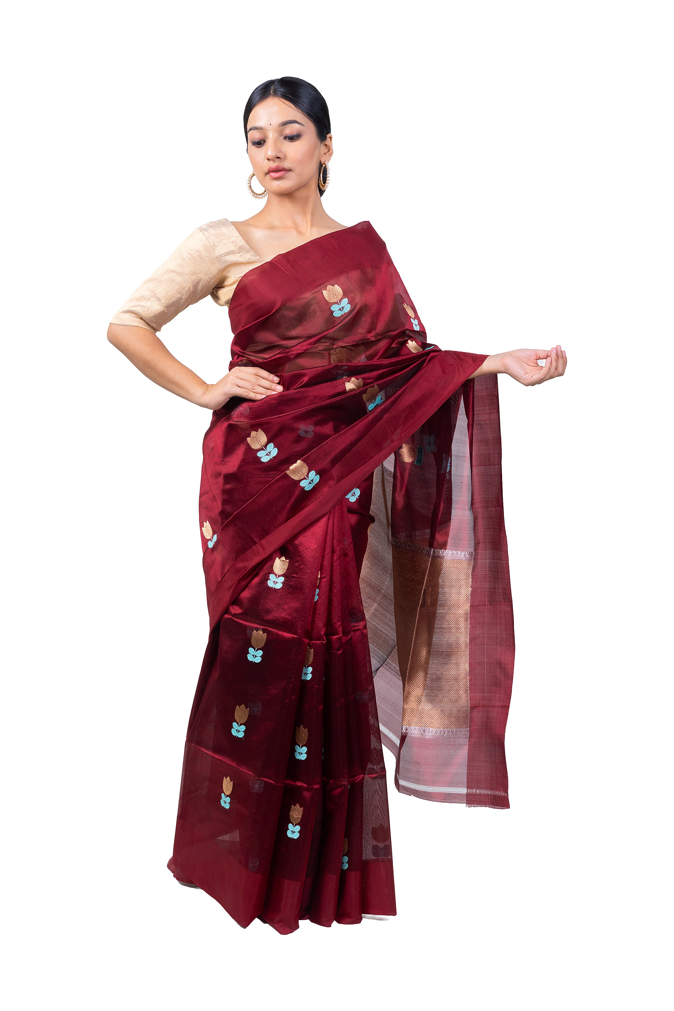 Woman wearing a maroon saree with intricate patterns on a white background