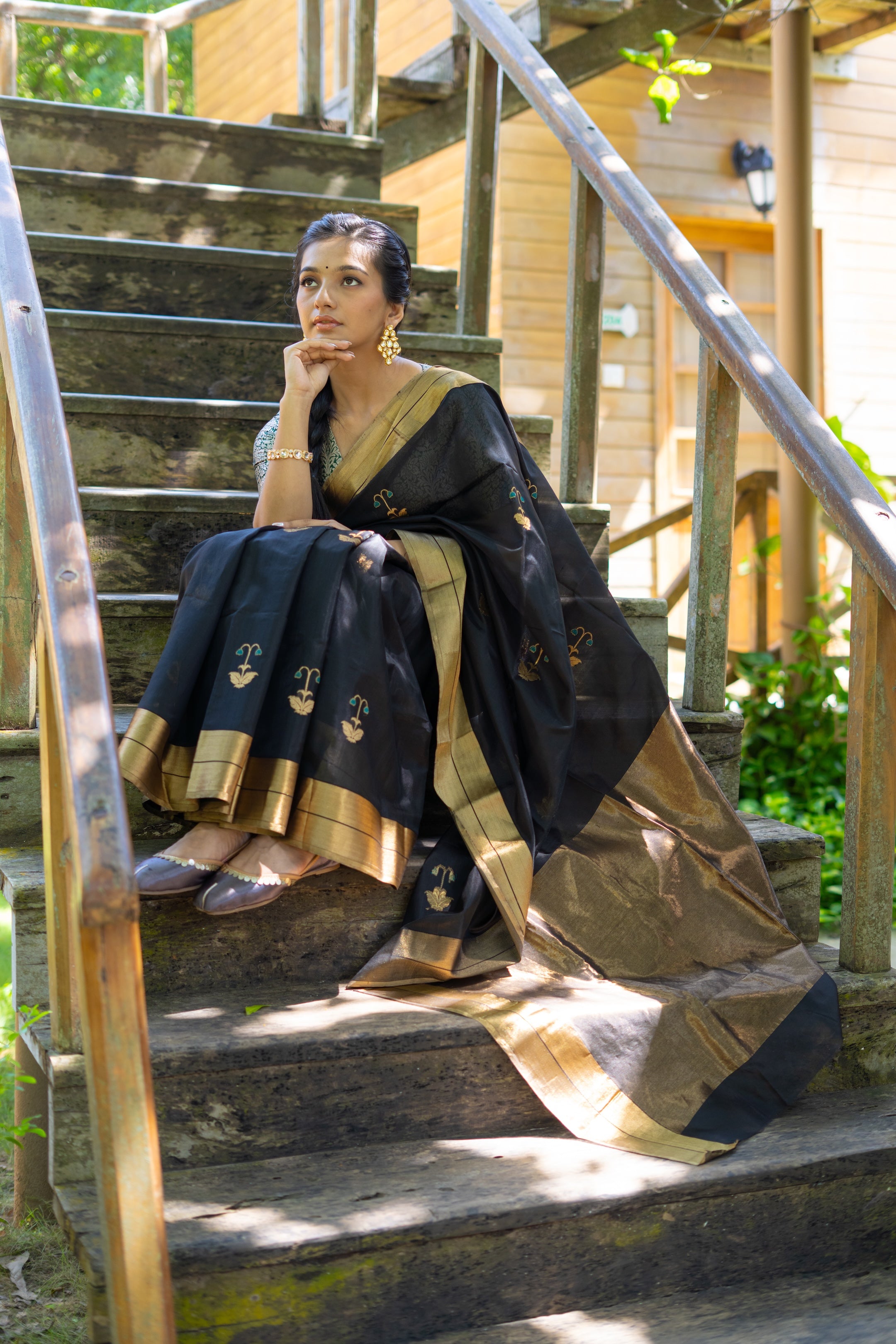 Woman in a traditional saree sitting on outdoor steps.